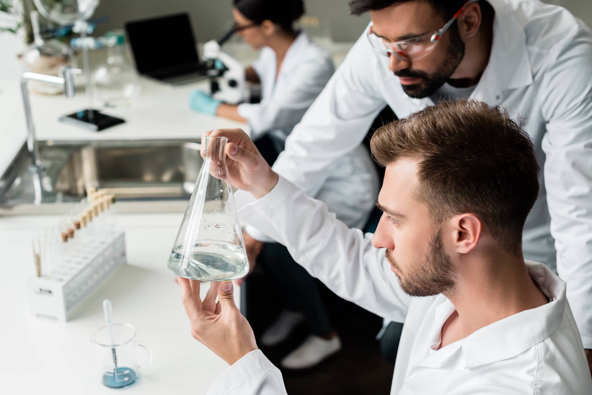 young-male-chemists-in-lab-coats-examining-reagent-2023-11-27-05-04-43-utc